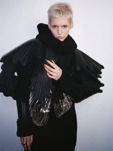 Model Paulina Bricca posing in a sculptural black jacket with layered shoulder details and metallic fringe for Elle Kazakhstan.