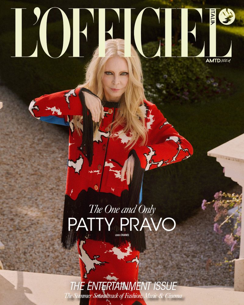Patty Pravo on L'Officiel Italia July 2026 cover wearing a red patterned fringe jacket standing in a garden