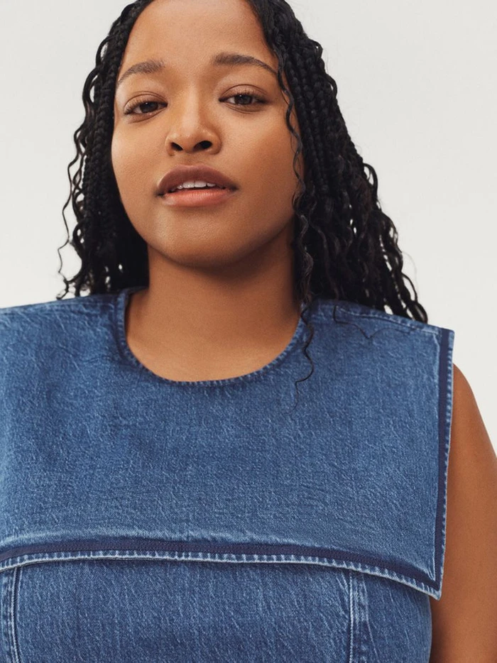 Model Imani Randolph wears a blue denim top with a wide square sailor collar against a light studio backdrop.