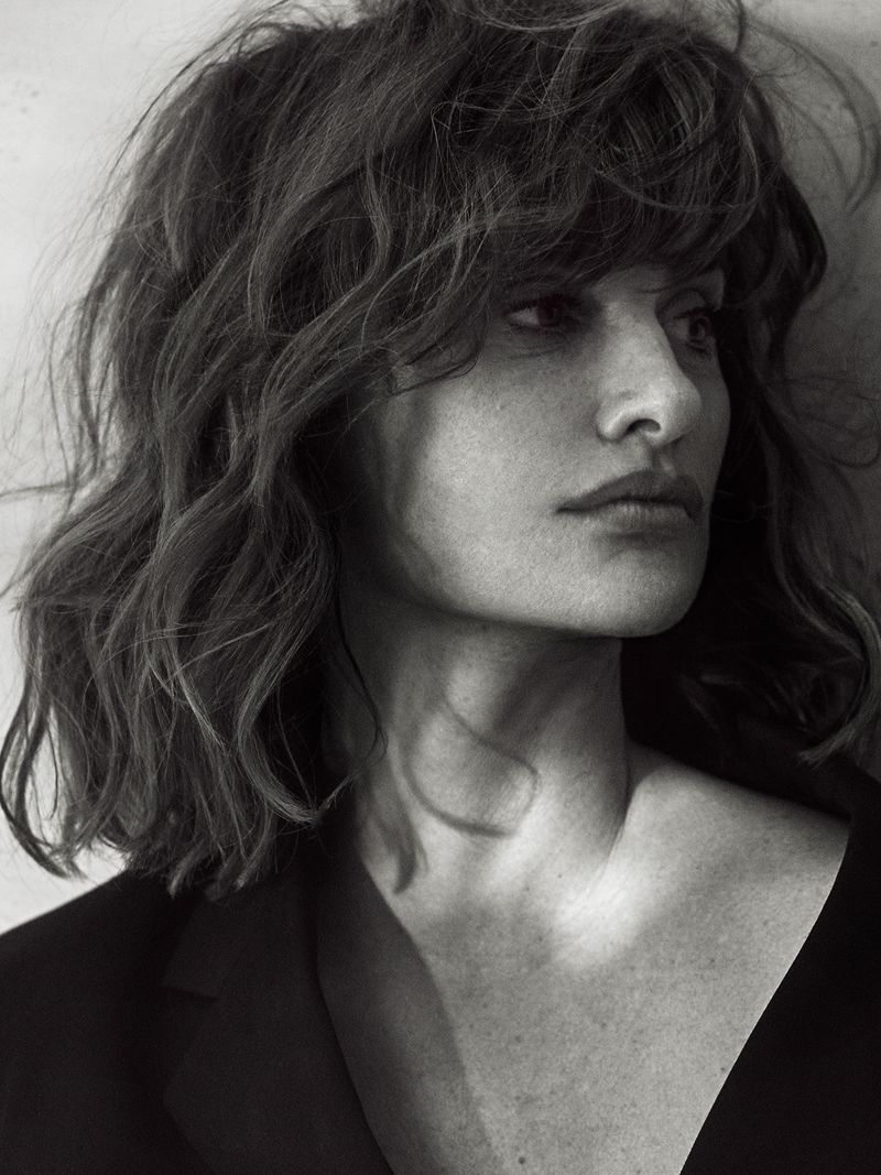 Monochrome portrait of Penelope Cruz with textured dark hair and a black blazer against a light wall