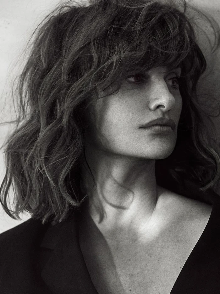Monochrome portrait of Penelope Cruz with textured dark hair and a black blazer against a light wall