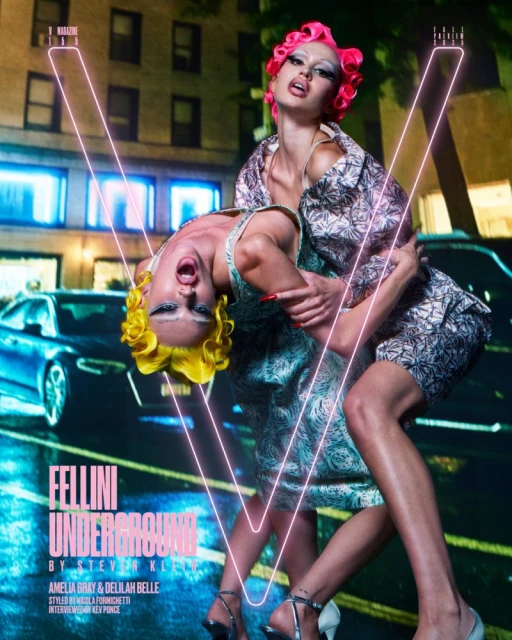 Two models in haute couture embrace in an urban setting at night, under neon lighting, captured in a fashion editorial photograph.