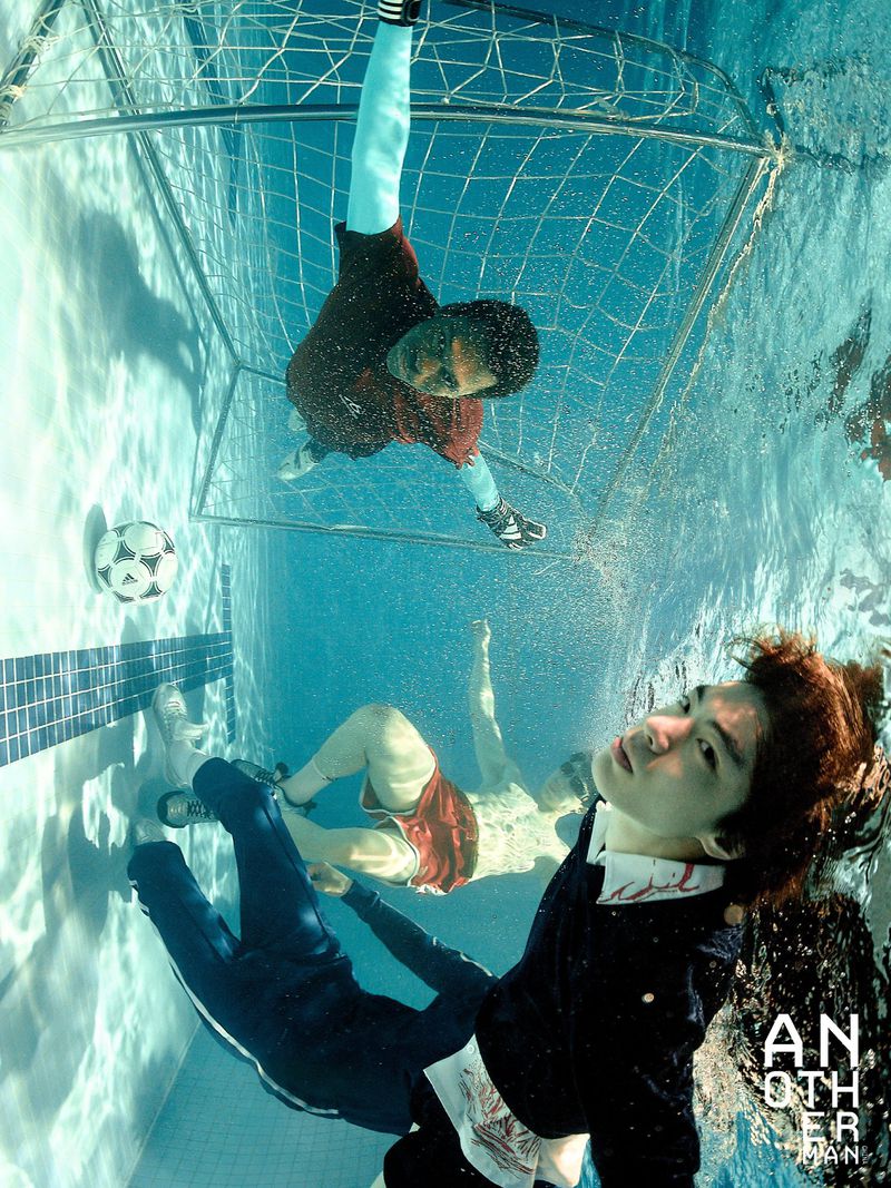 Underwater shot of two men playing soccer in a swimming pool with a goal and soccer ball, photographed for FIFA by AnOther Man China.