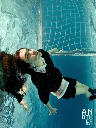 Model Woo Wu floating submerged underwater wearing a black polo shirt and shorts beside a soccer net for AnOther Man China.