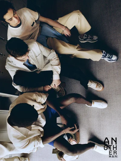 High-angle view of three male models seated on the floor in casual menswear for AnOther Man China.