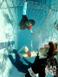 Underwater shot of two men playing soccer in a swimming pool with a goal and soccer ball, photographed for FIFA by AnOther Man China.