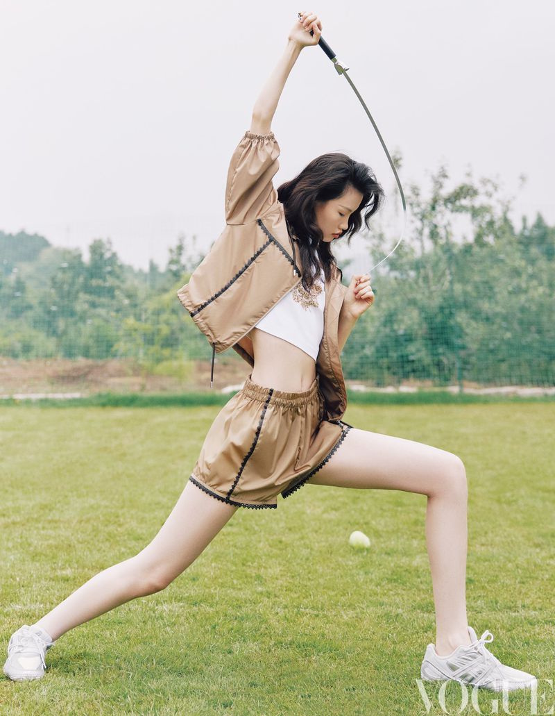 Model holding a sword in a dynamic lunge pose on a grassy field for Vogue China