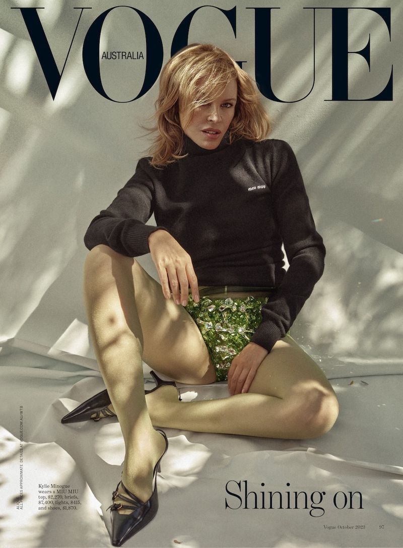 Vogue Australia cover featuring model with blonde hair, black turtleneck, and floral embellished bottoms, seated in a light-filled studio.