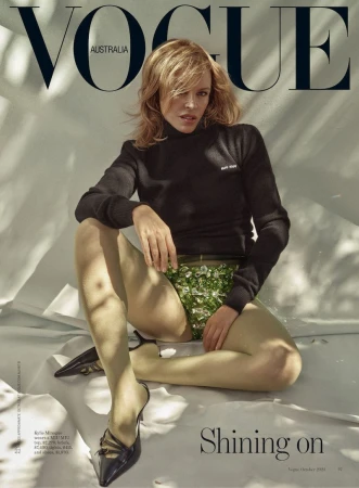 Vogue Australia cover featuring model with blonde hair, black turtleneck, and floral embellished bottoms, seated in a light-filled studio.