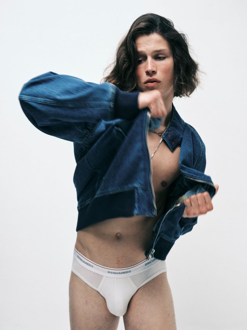 Model Lucas Barski wearing an open blue denim jacket and white briefs against a white studio background.