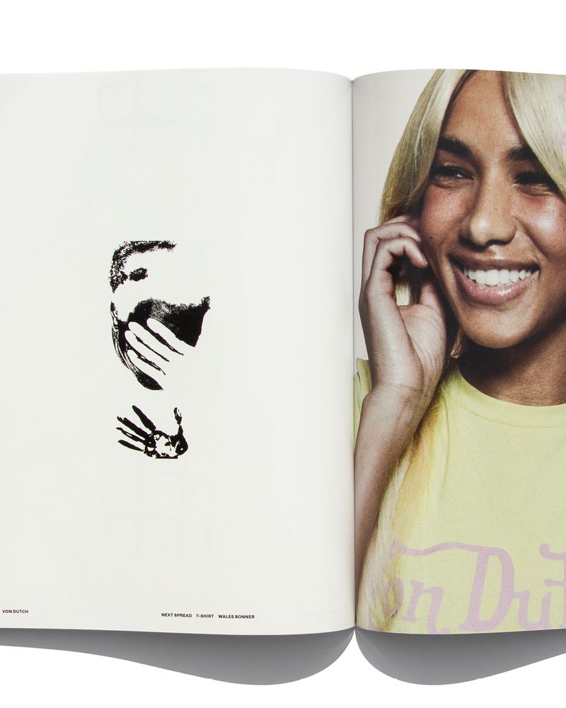 Open magazine spread showing a black graphic illustration on the left page and a smiling blonde woman in a yellow t-shirt on the right.