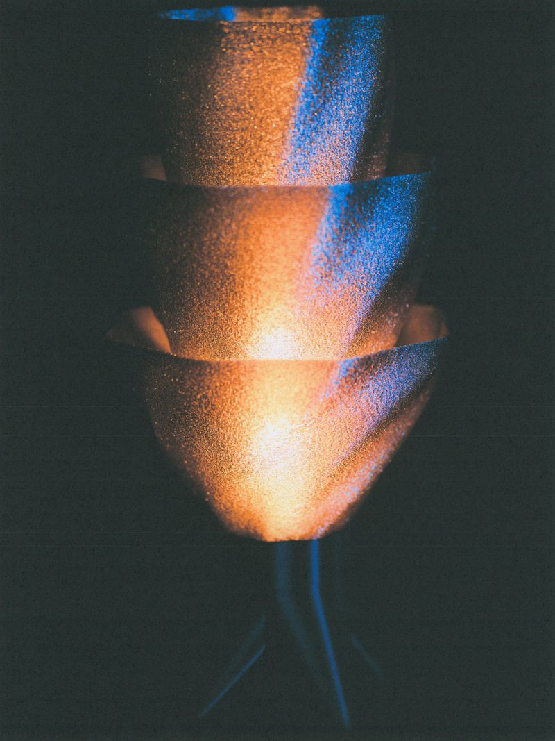 Tiered sculptural silhouette illuminated with warm amber and cool blue lighting against a dark background.