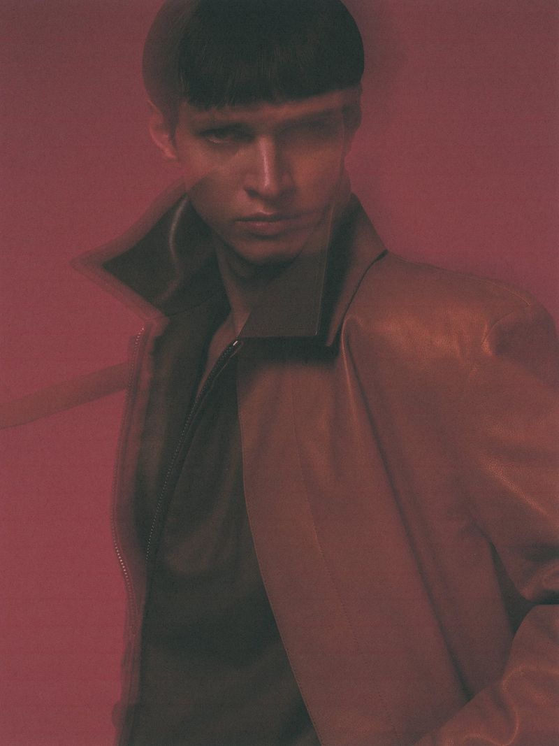 Model Kris Wardak wearing a high-collared brown jacket against a red-toned background for L'Officiel Hong Kong.