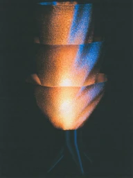 Tiered sculptural silhouette illuminated with warm amber and cool blue lighting against a dark background.