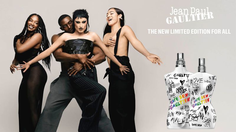 Gottmik and models posing beside Jean Paul Gaultier Pride limited edition fragrance bottles against a light studio backdrop.