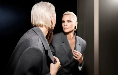 Model Nadja Auermann wearing a tailored grey blazer looking into a mirror reflection for the Ports 1961 campaign.