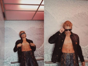 Model Owen Lindberg wearing patterned dark clothing and sunglasses against a textured background by Manny Roman.