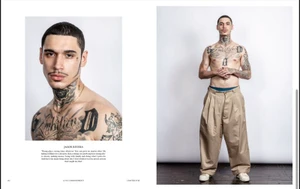 Portrait of a shirtless tattooed model in pleated trousers against a white backdrop for A Magazine Curated By editorial