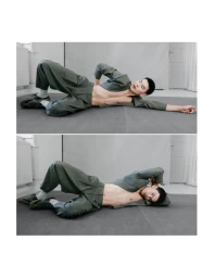 Model Buyant Munkhbat reclining on a grey studio floor wearing an open olive green suit for V MAN SEA.