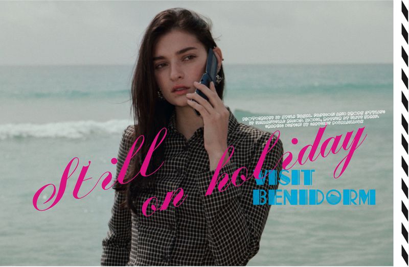 Model talking on a flip phone on a beach in a checked collared shirt with graphic magazine typography overlays.