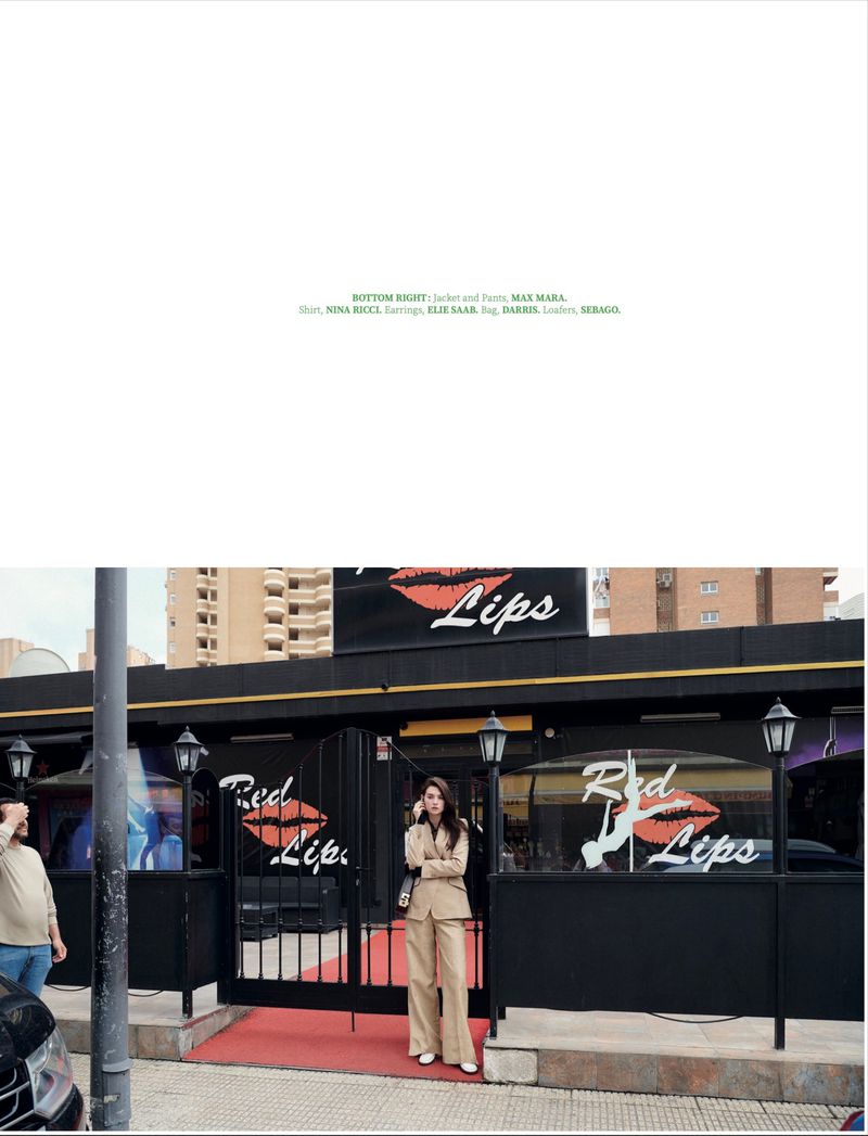 Model Ratner wearing a beige pantsuit standing outside the Red Lips club entrance in Benidorm for Heatline Magazine.