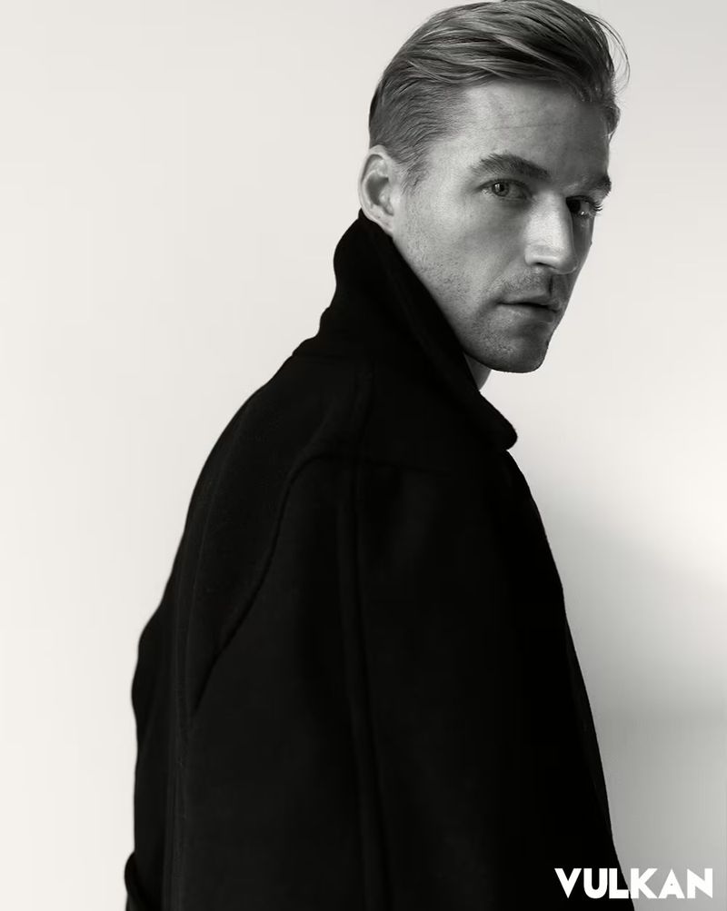 Portrait of a man in a black high-collar jacket against a plain white background for Vulkan Magazine.