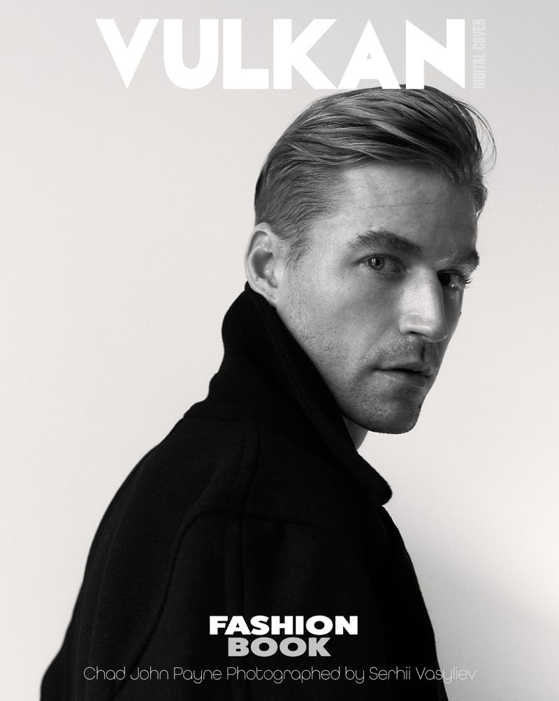 Black and white portrait of Chad John Payne wearing a dark high-collared jacket and looking over his shoulder against a plain backdrop.