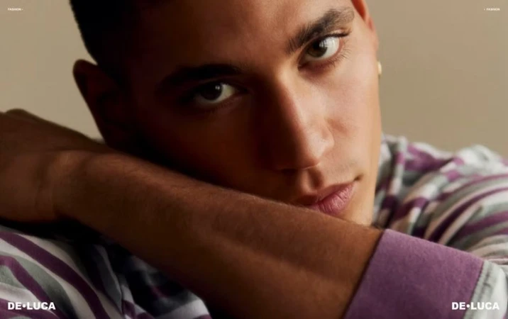 Close-up portrait of model Vincent Rayvon resting his chin on his arm while wearing a striped purple shirt.