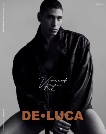 A person in a black jacket poses in a studio setting. The black and white portrait is a fashion editorial with modern typography.
