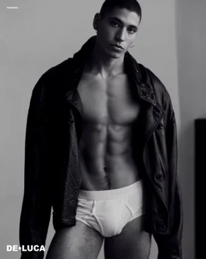 Monochrome portrait of a shirtless male model wearing a dark leather jacket and white briefs