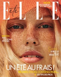 Close-up portrait of a freckled woman with green eyes under the dappled shadow of an orange woven hat on an Elle France cover.