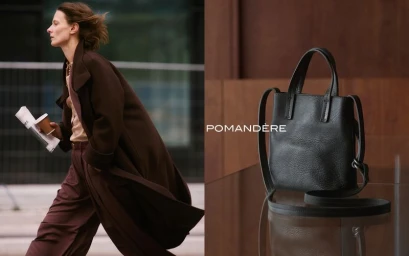 Model Tanya Ruban walking in a dark brown coat with a coffee cup beside a black textured leather Pomandère tote bag.