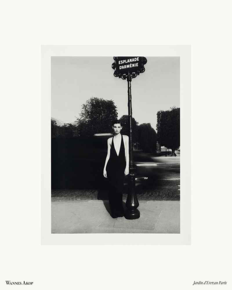Estella Nolan wearing a plunging black halter dress beside an ornate street sign post in Paris in black and white.