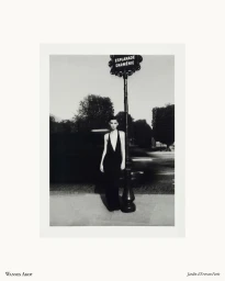 Estella Nolan wearing a plunging black halter dress beside an ornate street sign post in Paris in black and white.