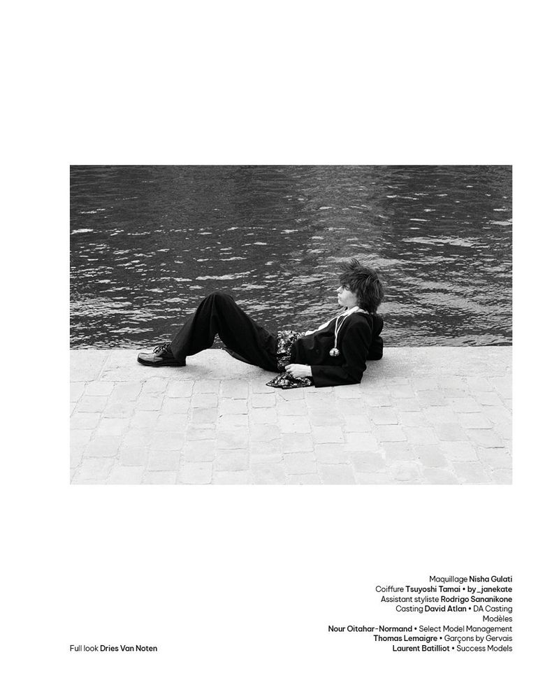 Model Laurent Batilliot reclining on a stone quayside beside river water in a black and white fashion editorial layout.