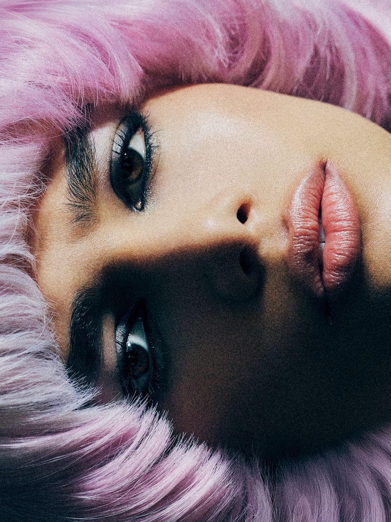 Close-up beauty portrait of model Aviana M framed by textured pastel pink and lilac hair.