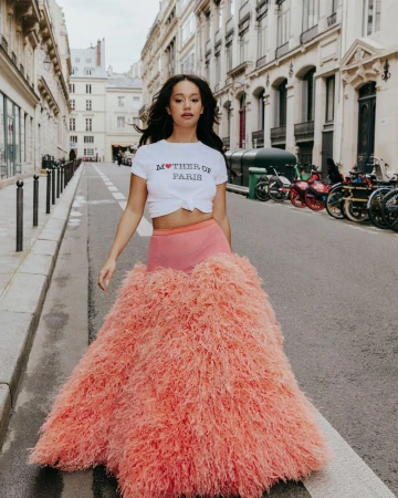 Woman walking on a Parisian street wearing a white t-shirt and a voluminous textured pink skirt for Madame Figaro.