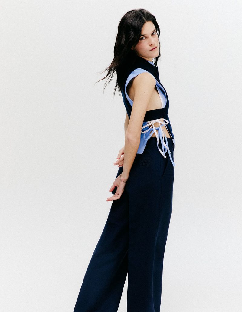 Suzanne Lindon posing in a navy sleeveless cutout top and matching wide-leg trousers against a plain white studio background.