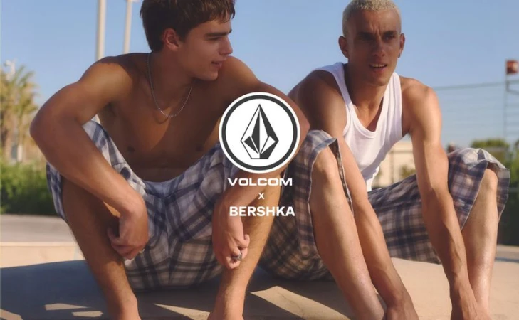 Two young men seated outdoors in skatewear wearing plaid shorts and a white tank top for Volcom x Bershka.