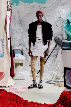 Quadri Ajao in a black cropped jacket, layered white skirt, and textured leg warmers on the Charles Jeffrey Loverboy S/S 27 set.