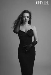 Monochrome fashion portrait of Daria Chernenko wearing a black strapless dress and sheer opera gloves against a grey background.