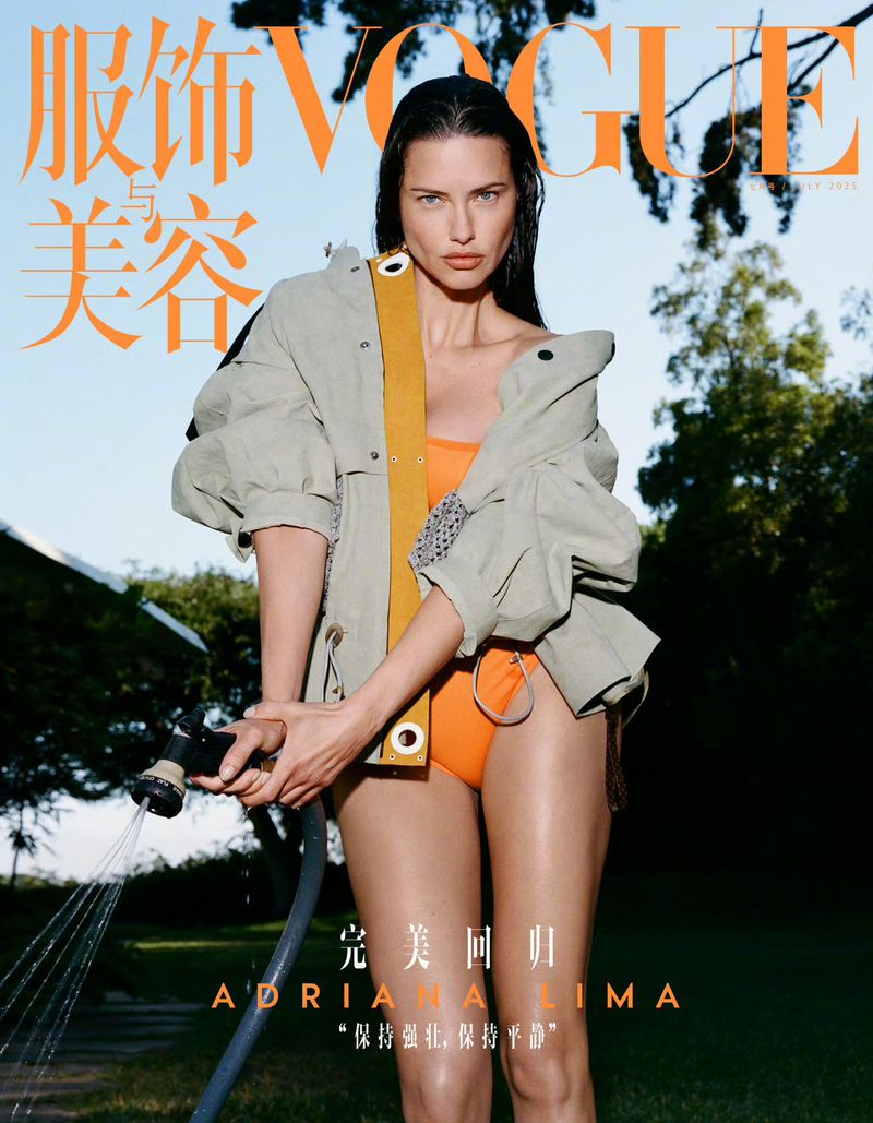 Vogue cover featuring Adriana Lima in swimwear and a jacket, holding a garden hose, set against a lush outdoor backdrop under a bright sky.