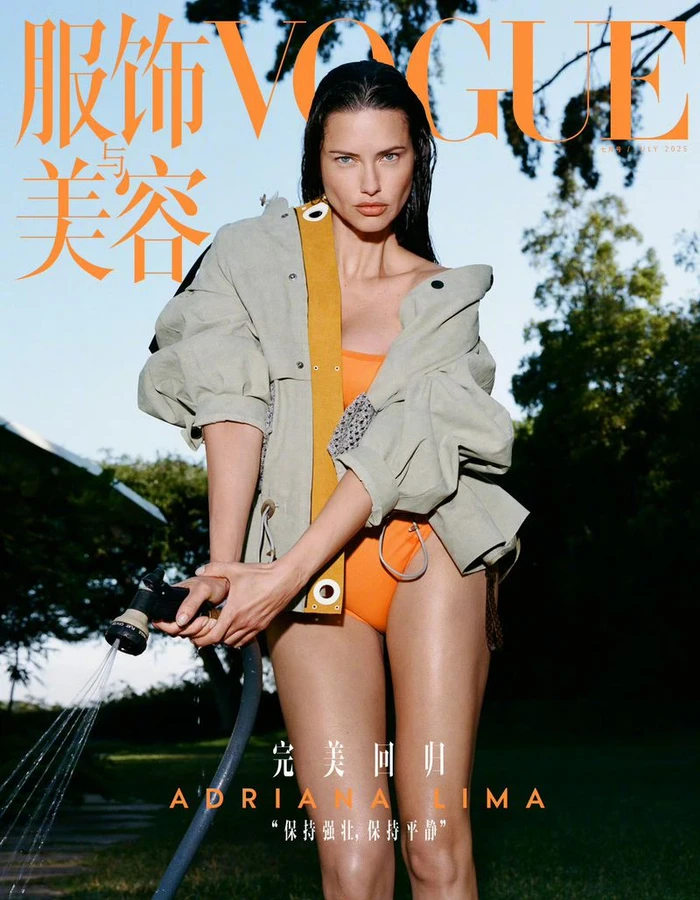 Adriana Lima in an oversized beige utility jacket and orange swimsuit holding a spraying garden hose for Vogue China.