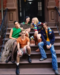 Five models sit together on a brownstone stoop wearing casual colorful clothing around a Marc Jacobs Perfect perfume bottle.