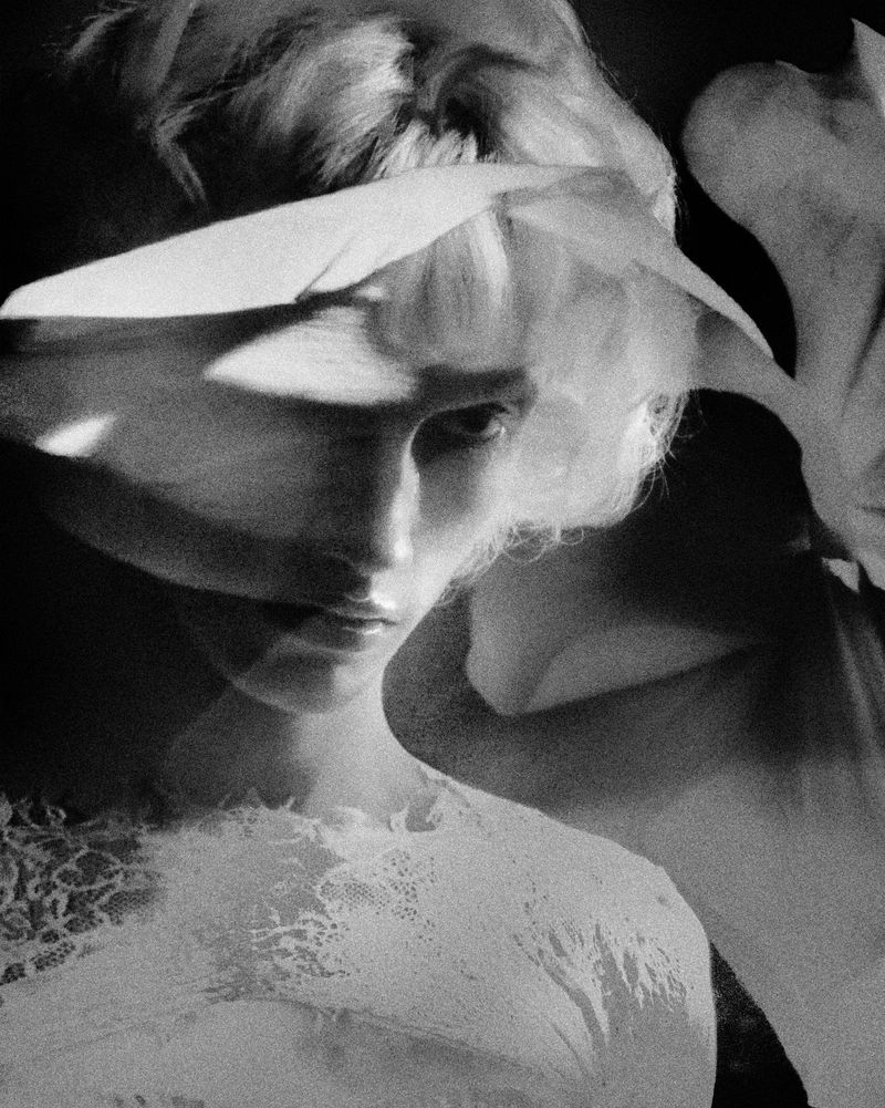 Monochrome close-up portrait of model Maty Drazek in a white lace top with floral shadow reflections across the face.