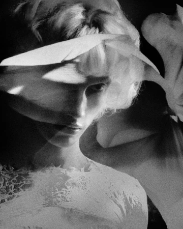 Monochrome close-up portrait of model Maty Drazek in a white lace top with floral shadow reflections across the face.