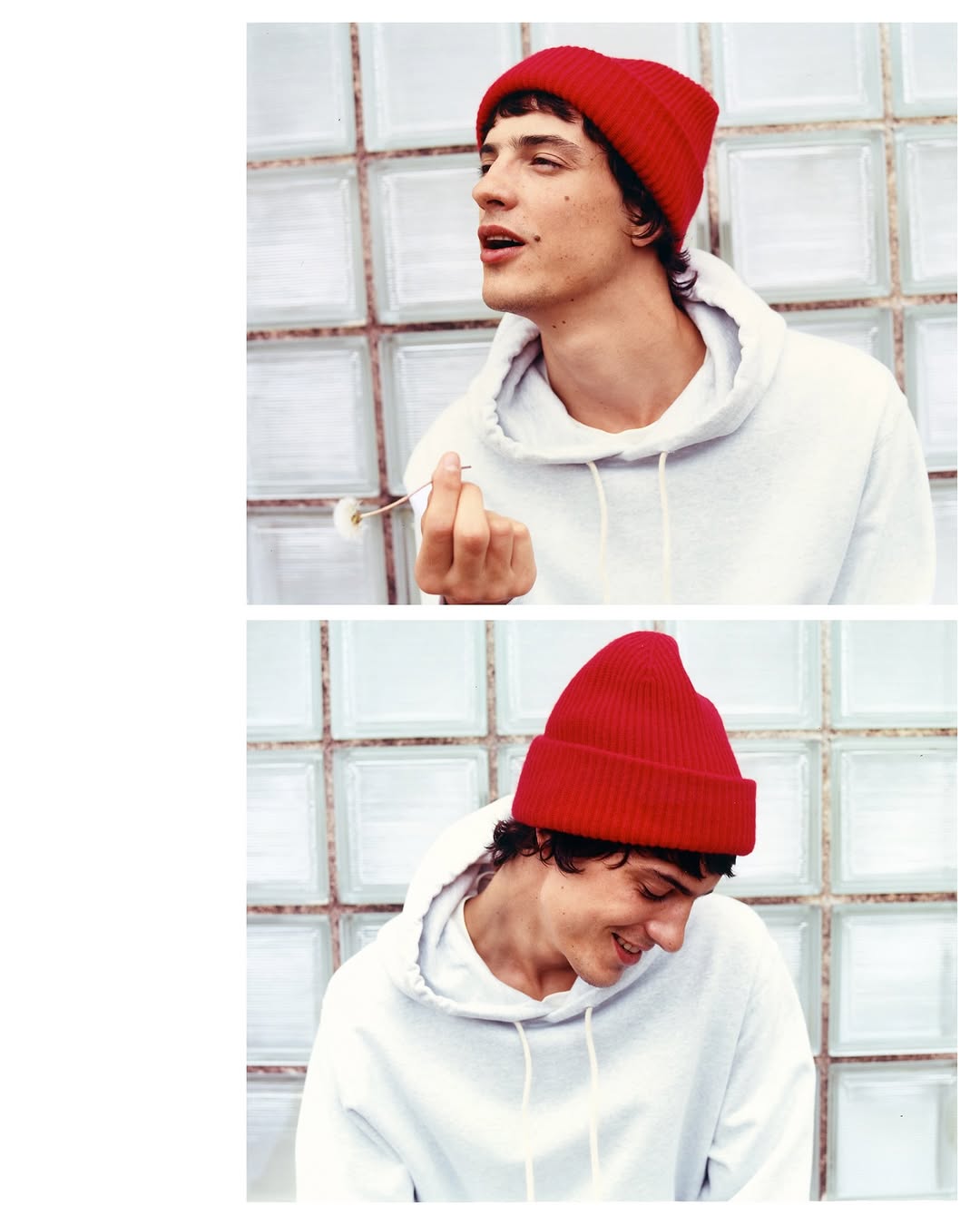 A young adult male wearing a red beanie and white hoodie is captured in a close-up shot against a textured glass block wall.