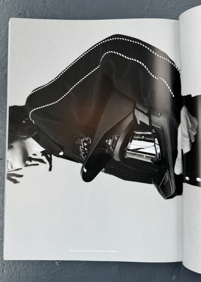 Black and white photograph of a reflective car hood with an abstract design, captured in a magazine spread under bright lighting.