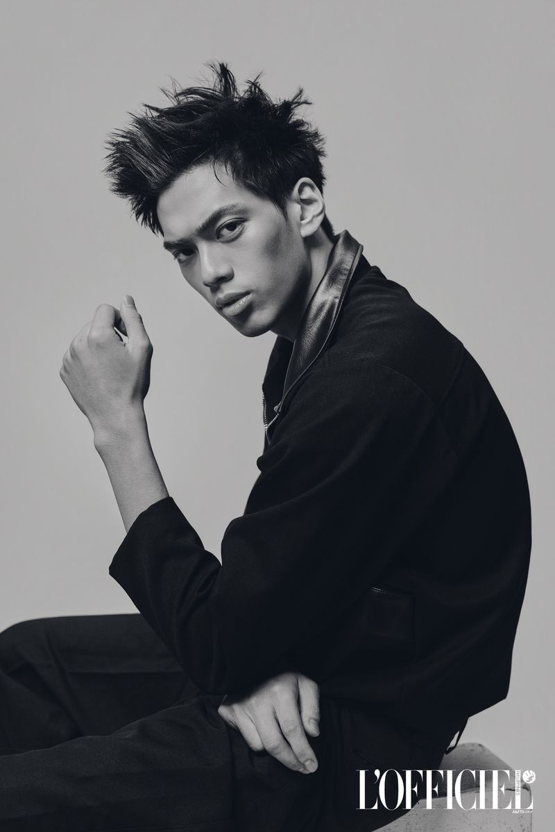 Monochrome portrait of a male model in a black collared jacket seated against a studio backdrop for L'Officiel Philippines.