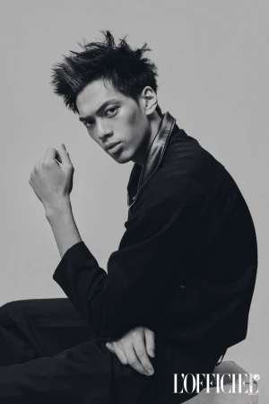 Monochrome portrait of a male model in a black collared jacket seated against a studio backdrop for L'Officiel Philippines.